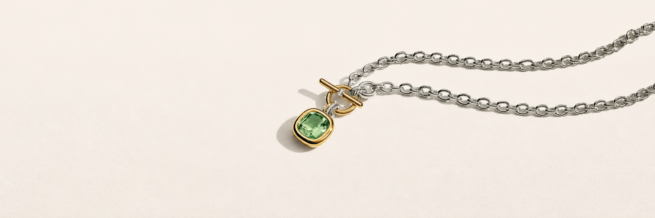 Silver chain with green stone toggle pendant on cream background
